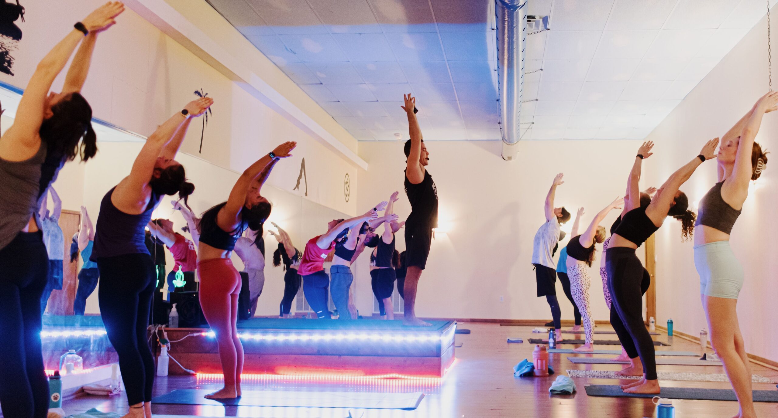 Group fitness class performing high kicks in a brightly lit studio.